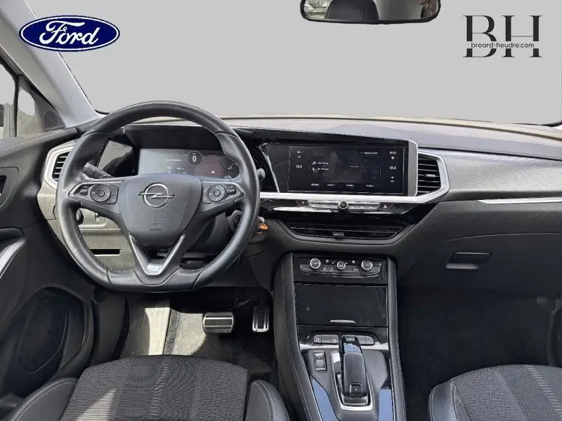 Vue intérieure avant de l'Opel Grandland 2023, tableau de bord noir avec écran tactile et volant cuir multifonction.