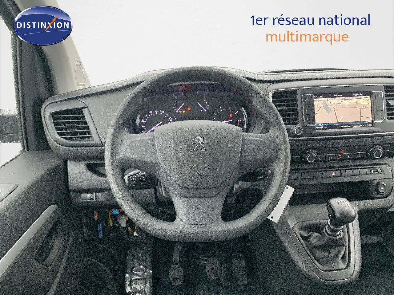 Vue intérieure centrée sur le volant Peugeot et le tableau de bord avec écran tactile et levier de vitesses manuel.