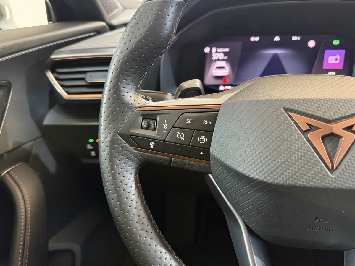 Gros plan sur le volant cuir perforé noir avec commandes multifonctions et logo CUPRA cuivré du Formentor 2023.