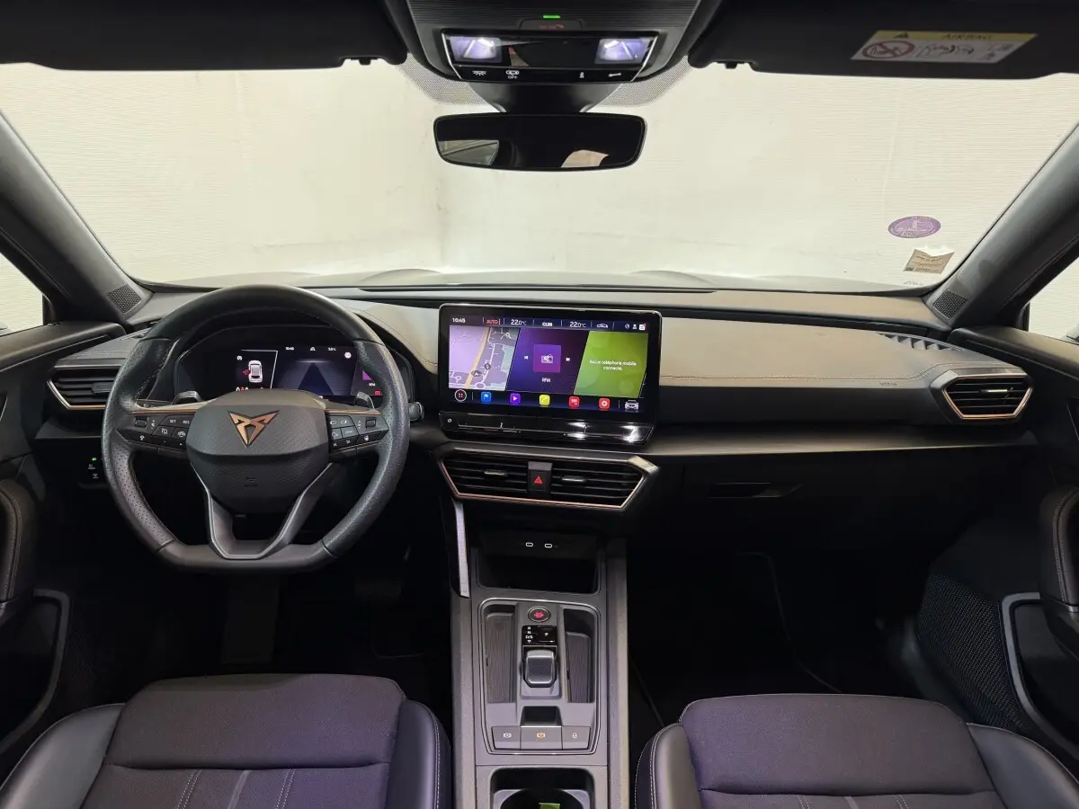 Intérieur noir du CUPRA Formentor 1.5 TSI 2023 vu de face, tableau de bord moderne avec écran tactile central lumineux.