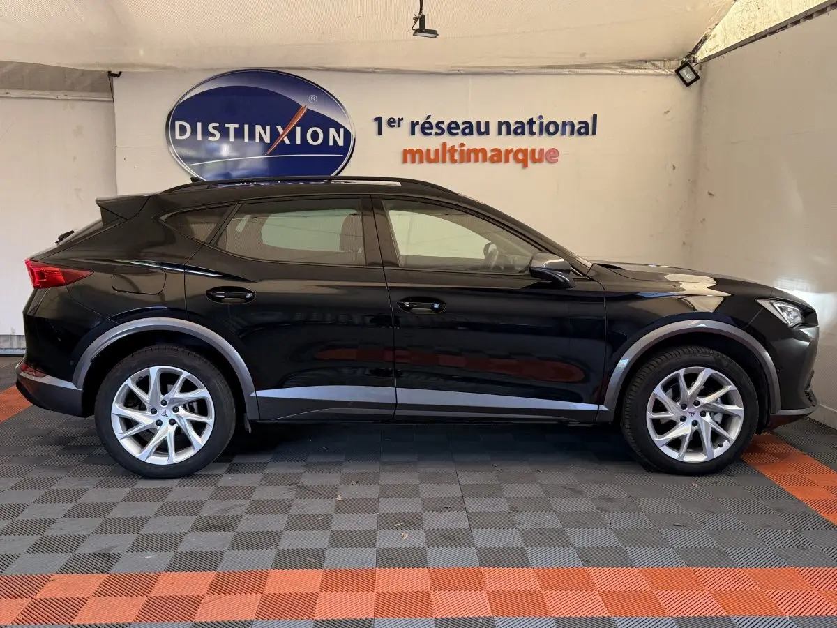 Profil côté gauche d'un SUV CUPRA Formentor noir 2023 avec jantes alliage et protections grises sous un panneau Distinxion.