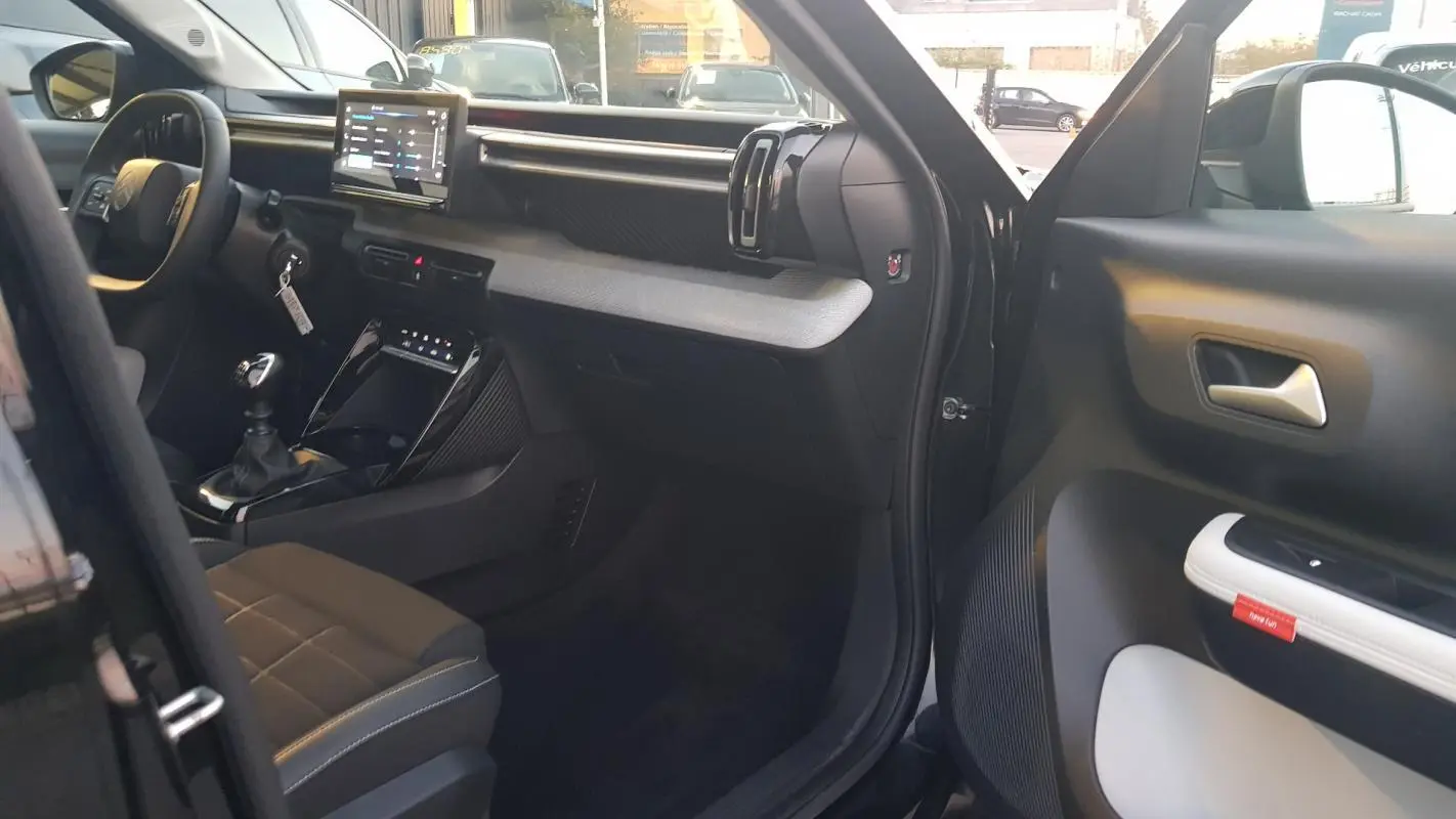 Intérieur avant droit de la Citroën C3 noire 2025, avec tableau de bord moderne et boîte manuelle visible.