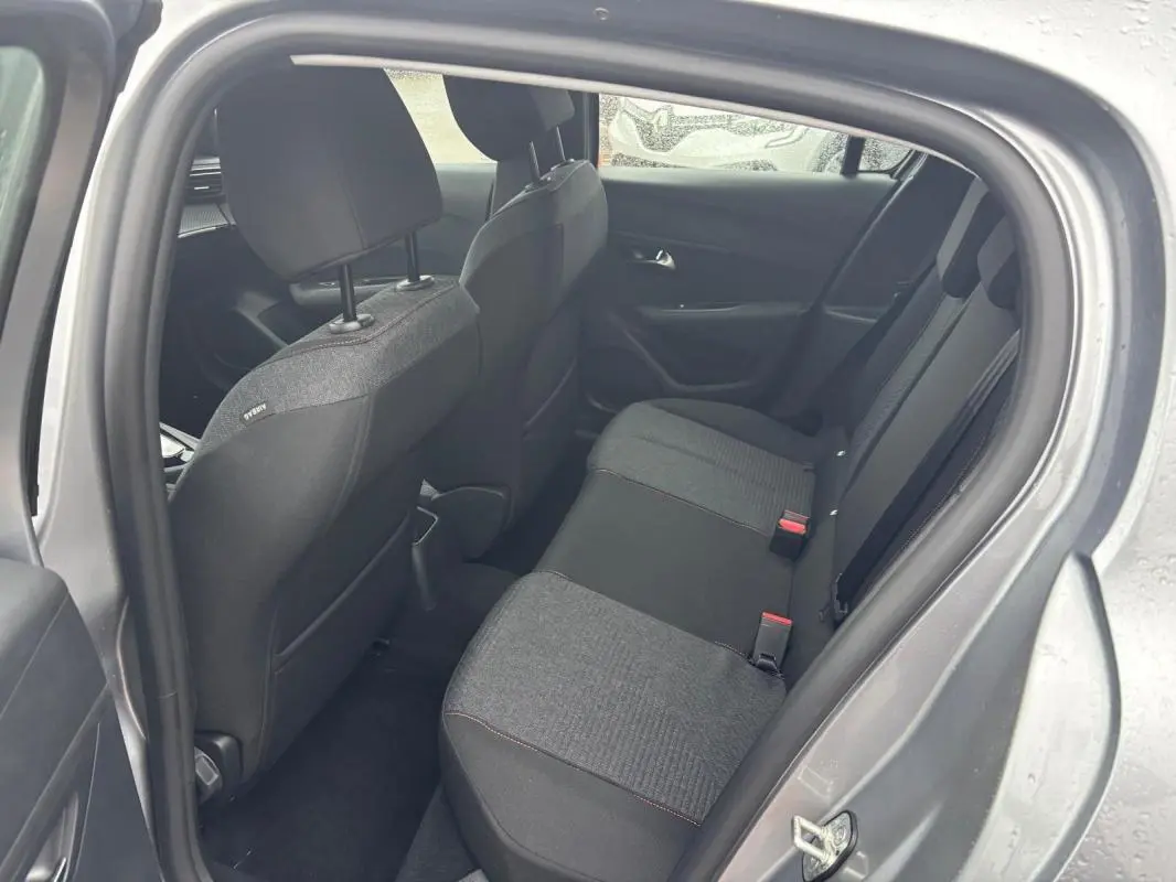 Vue intérieure côté droit des sièges arrière gris foncé d'une Peugeot 208 Hybrid 100 e-DCS6 Style 2025 avec portières ouvertes.