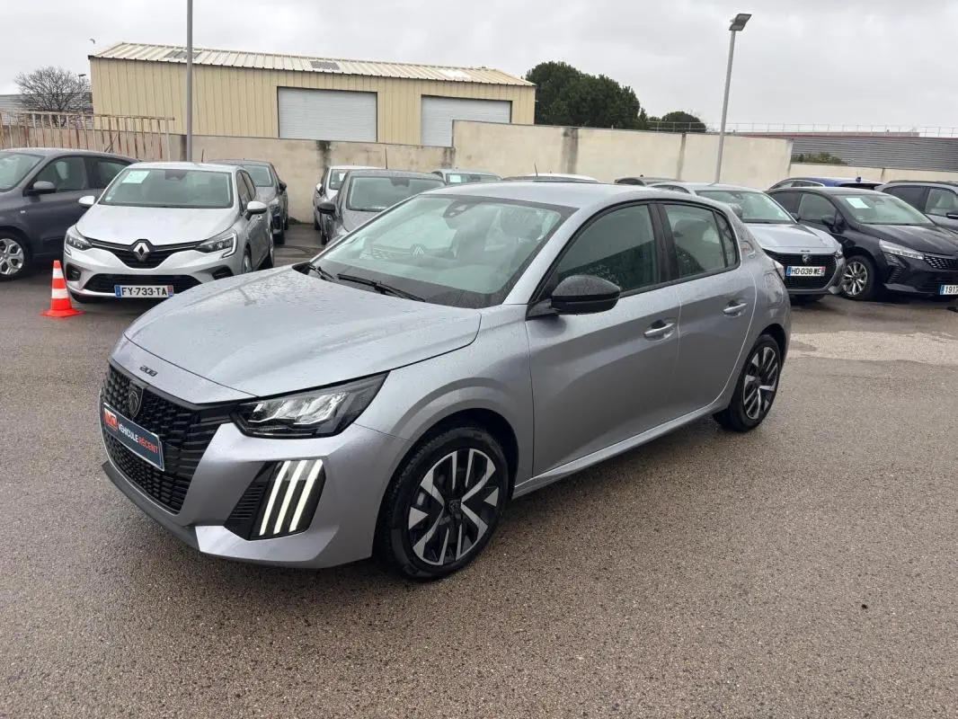 Peugeot 208 Hybrid gris vue 3/4 avant droit, feux LED diurnes verticaux et jantes 16 pouces stylisées.