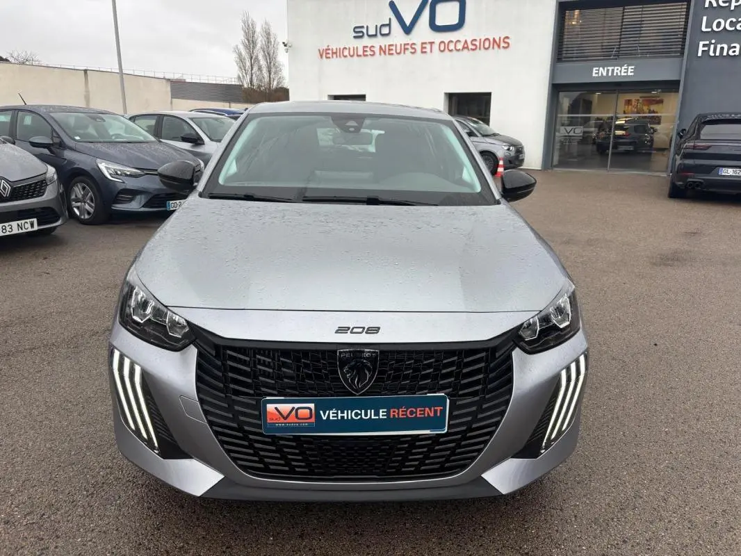 Vue avant d'une Peugeot 208 Hybrid gris métallisé avec calandre noire et feux diurnes LED en forme de griffes.