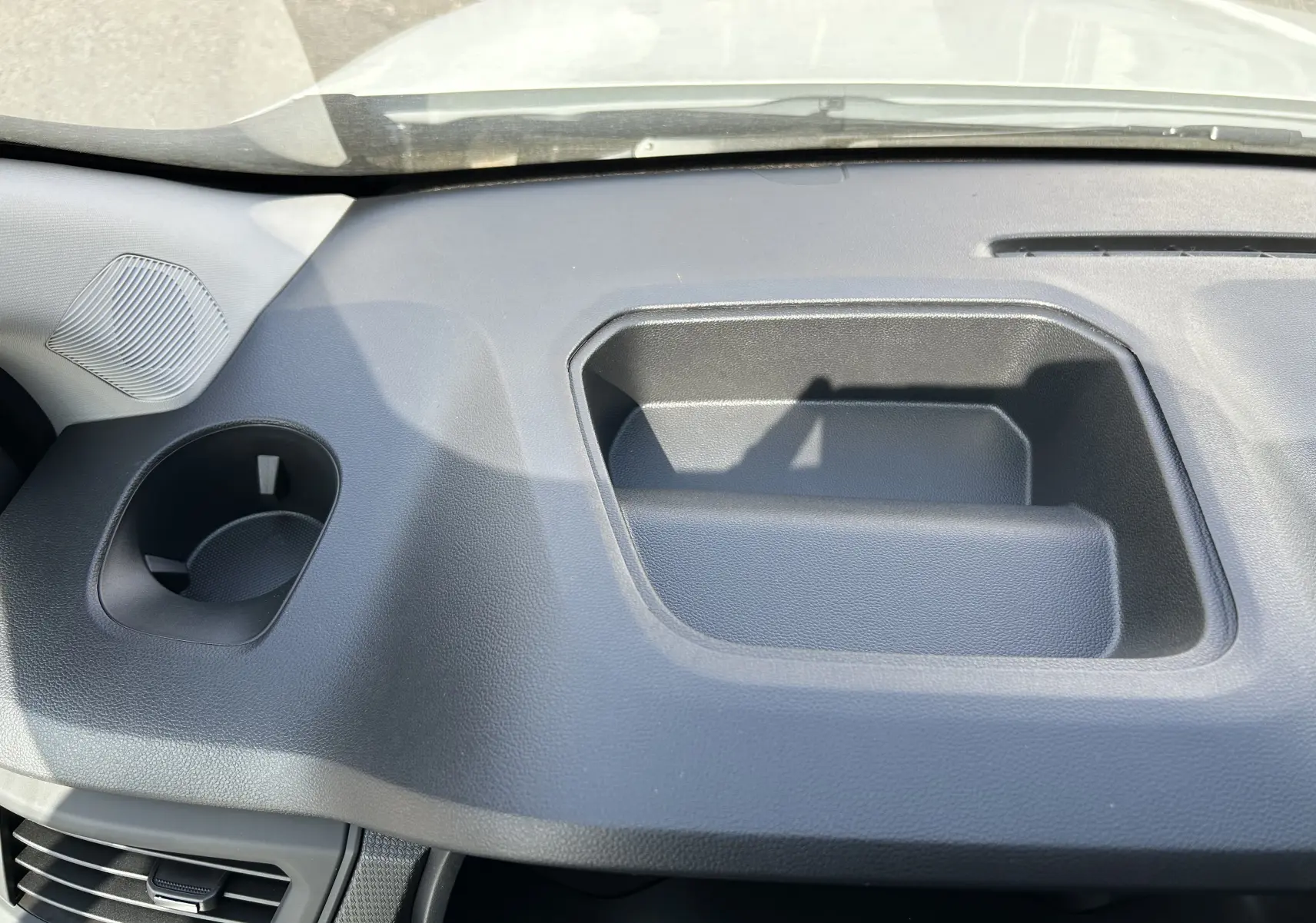 Détail intérieur du tableau de bord noir du Renault Trafic cabine approfondie, avec rangement intégré et porte-gobelet.
