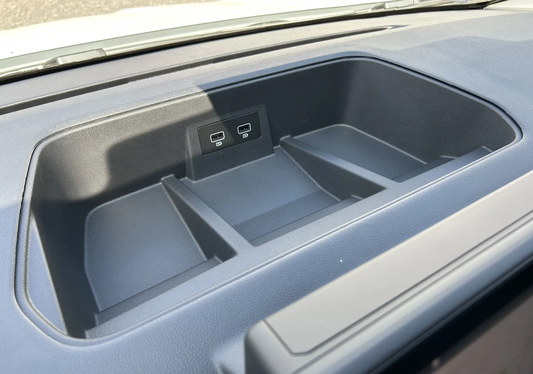 Gros plan sur le rangement central noir du tableau de bord du Renault Trafic cabine approfondie avec ports USB intégrés.