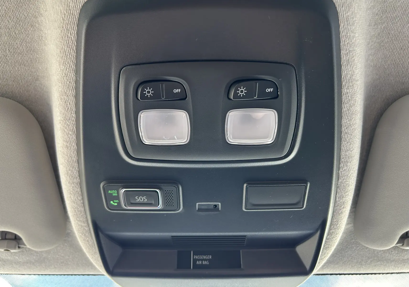 Vue en gros plan du plafonnier intérieur noir avec commandes d’éclairage et bouton SOS du Renault Trafic blanc.