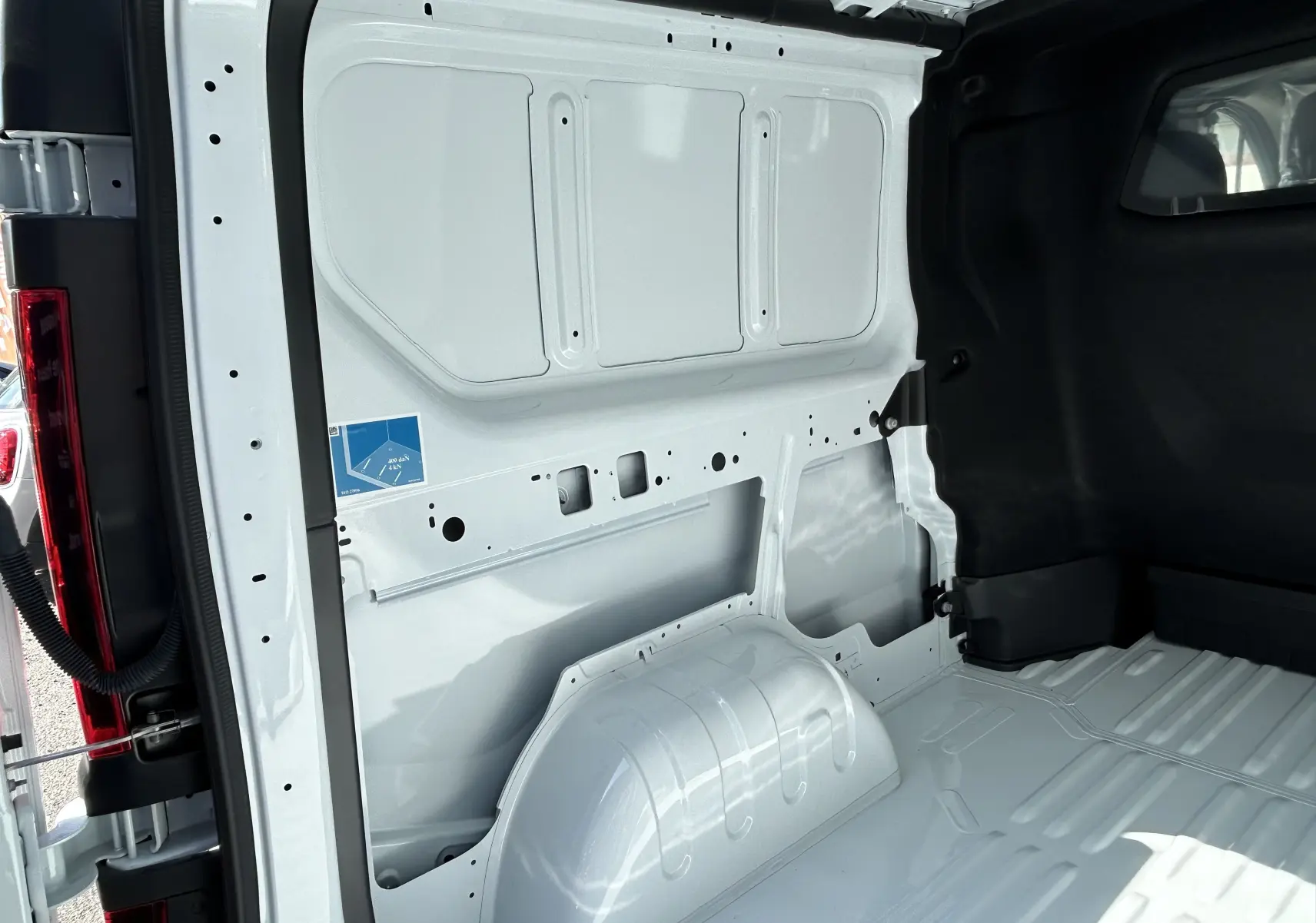 Vue intérieure arrière droite du Renault Trafic cabine approfondie blanc, montrant la paroi métallique et le plancher nu du coffre.