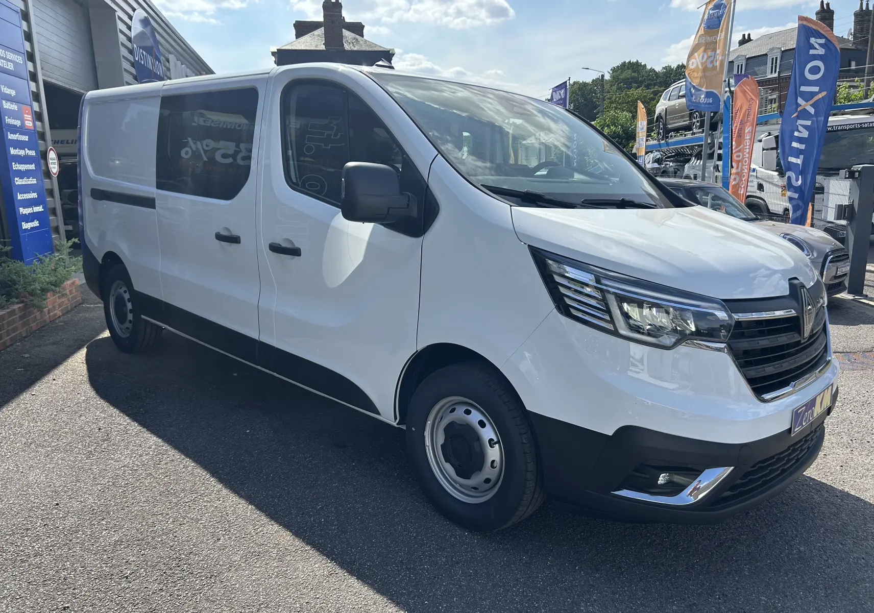 Vue 3/4 avant droit d’un Renault Trafic cabine approfondie blanc avec portes latérales coulissantes et projecteurs modernes.
