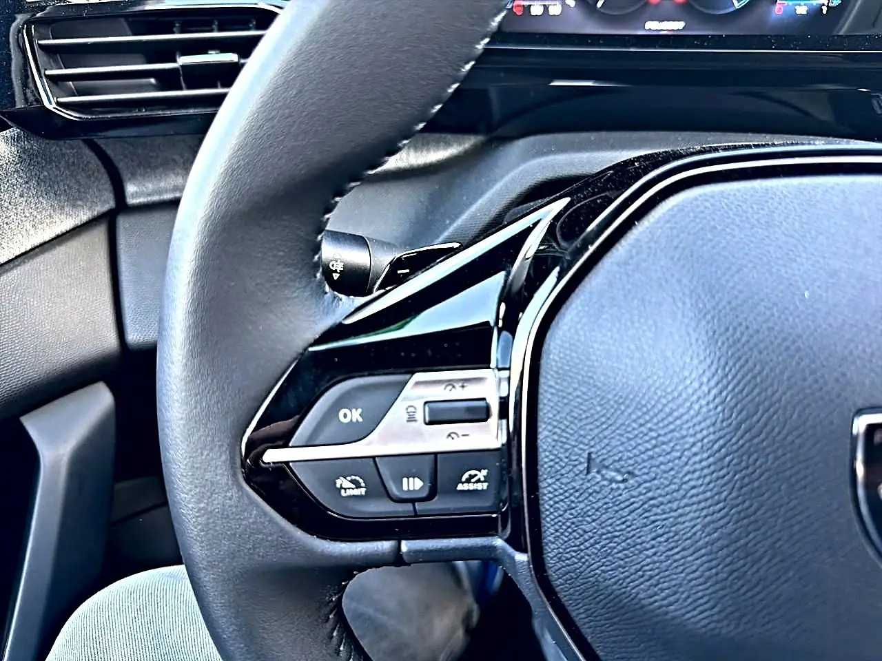Gros plan sur le volant multifonction noir de la Peugeot 308 2025, avec commandes intégrées côté gauche.