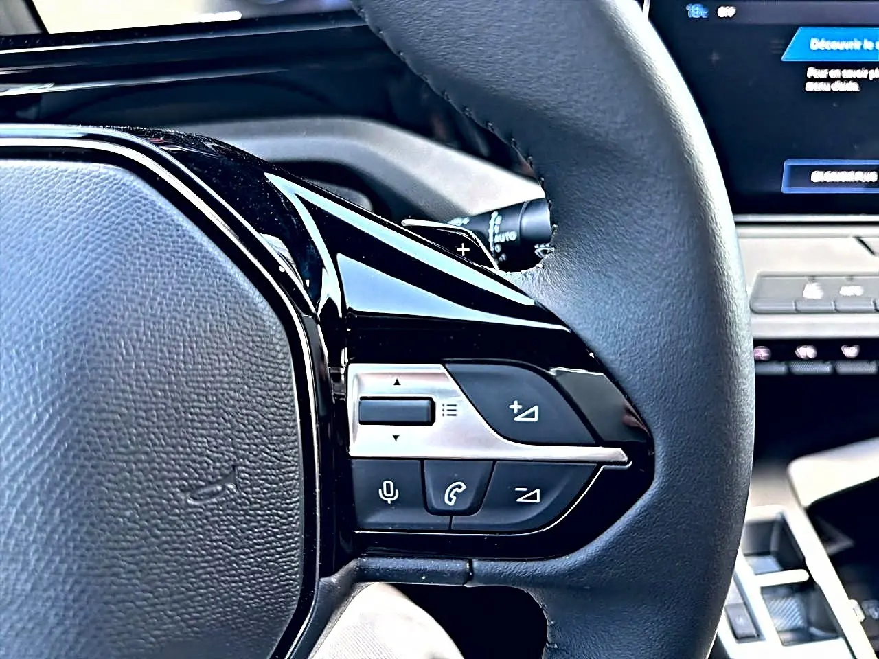 Gros plan sur le volant multifonction noir de la Peugeot 308 2025 avec commandes audio et téléphone intégrées.