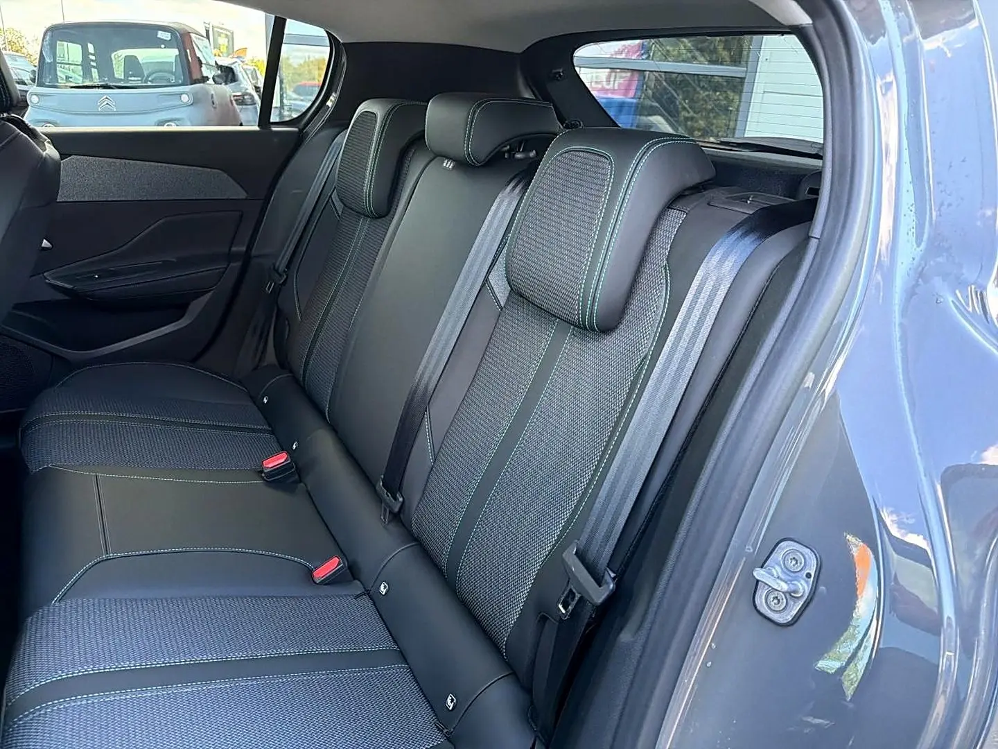 Vue intérieure côté droit sur la banquette arrière en tissu et cuir noir avec surpiqûres vertes d'une Peugeot 308 gris selenium.