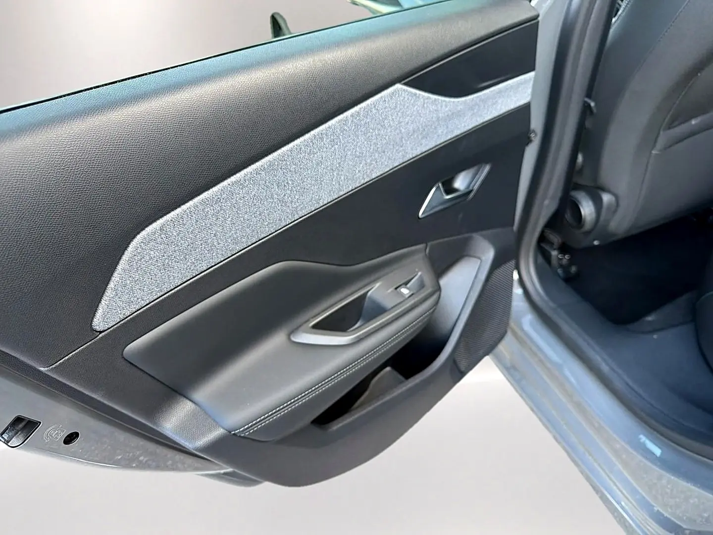 Gros plan sur la porte arrière gauche gris selenium d’une Peugeot 308 2025 avec habillage tissu clair et commandes de vitre.