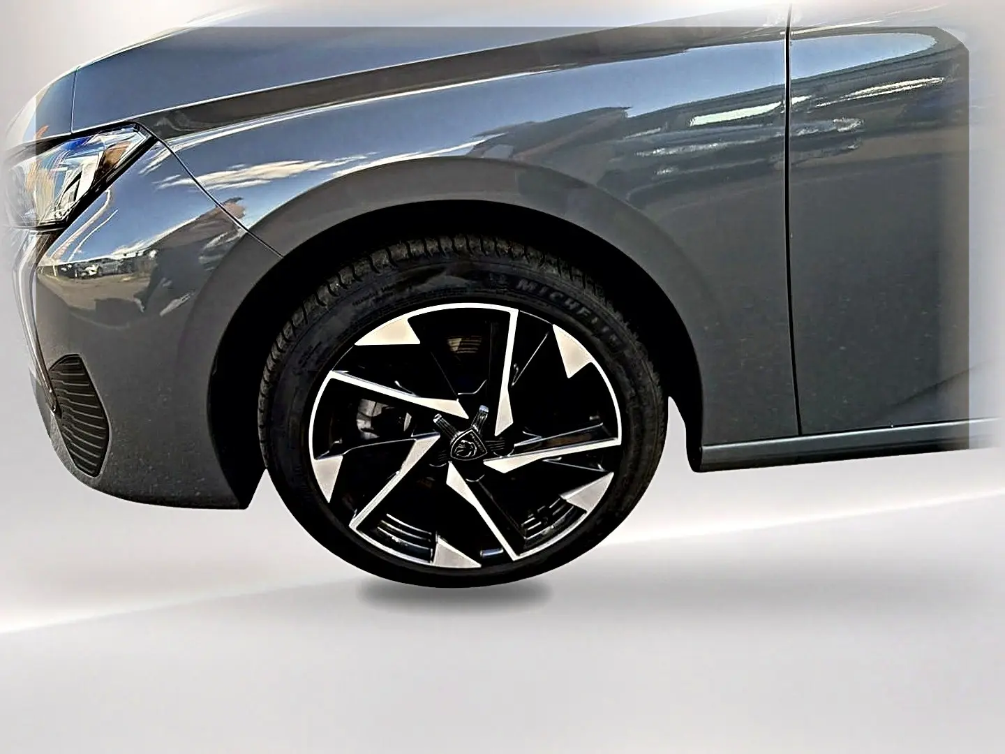 Gros plan sur la roue avant gauche et l'aile d'une Peugeot 308 gris selenium avec jante alu noire et argent.