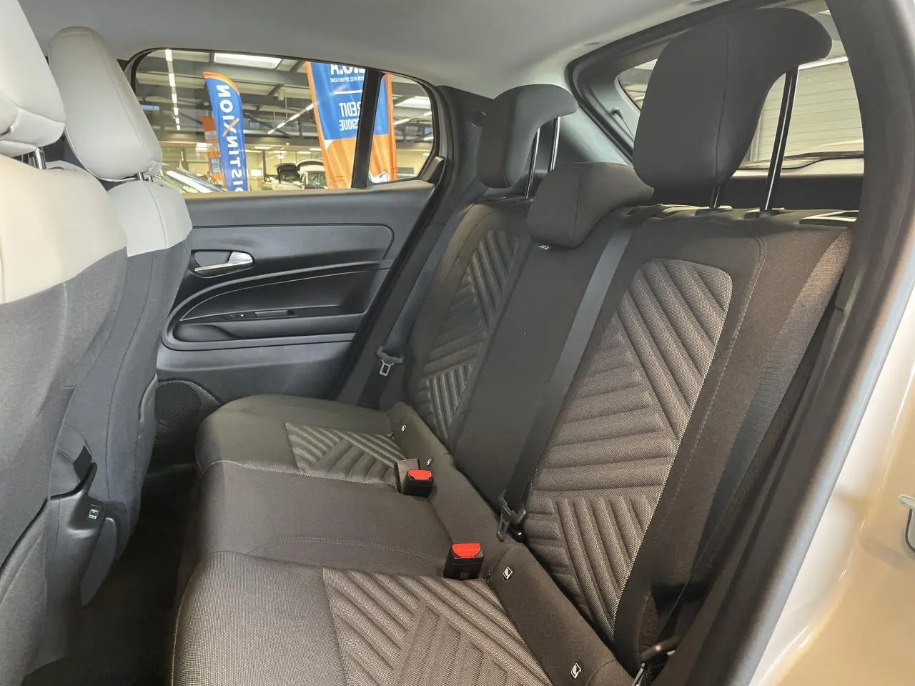 Vue intérieure côté droit des sièges arrière en tissu noir avec motifs géométriques d'une Fiat 600 beige métallisé.