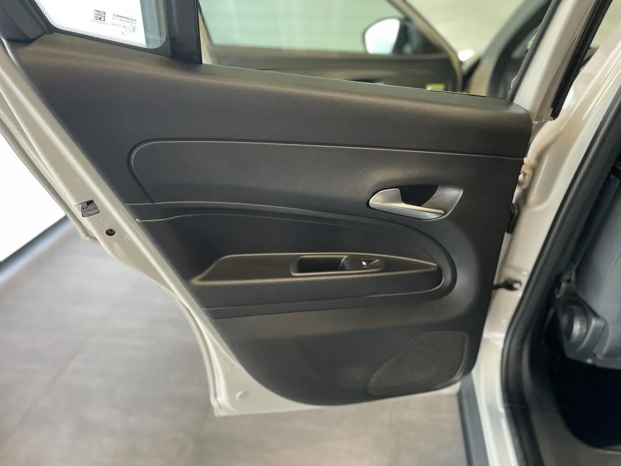 Gros plan sur la porte arrière gauche beige métallisé d'une FIAT 600 Hybrid 2025 avec poignée intérieure chromée.