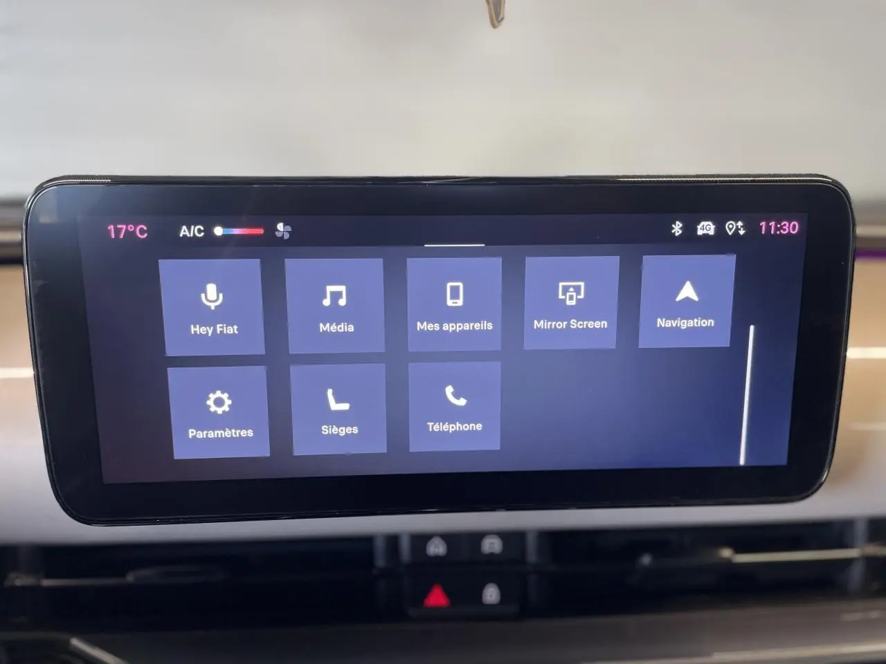 Écran tactile central affichant le système Uconnect dans un Fiat 600 beige métallisé, planche de bord claire visible en arrière-plan.