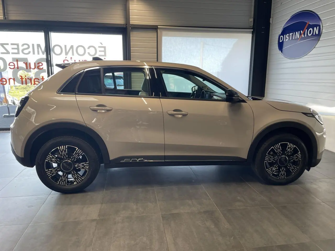 Profil latéral droit d'une FIAT 600 beige métallisé avec jantes alliage noires et logo 600 sur la bas de caisse.