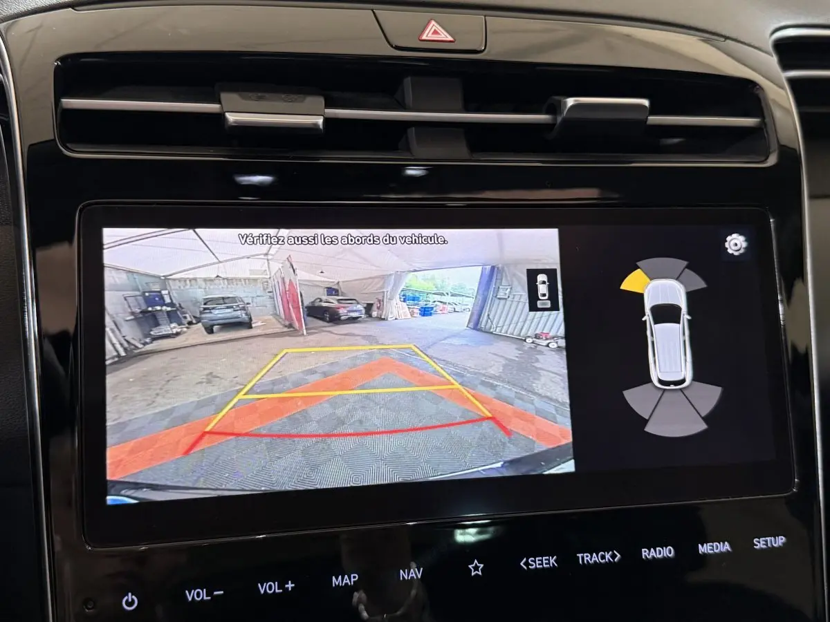 Écran tactile du Hyundai Tucson noir montrant la caméra de recul et l'aide au stationnement arrière.