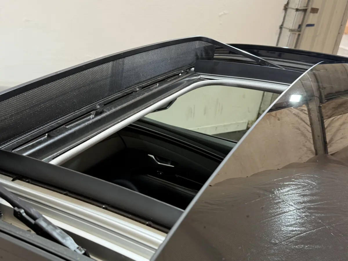 Toit ouvrant panoramique ouvert sur un Hyundai Tucson noir, vue rapprochée du toit et intérieur côté passager.