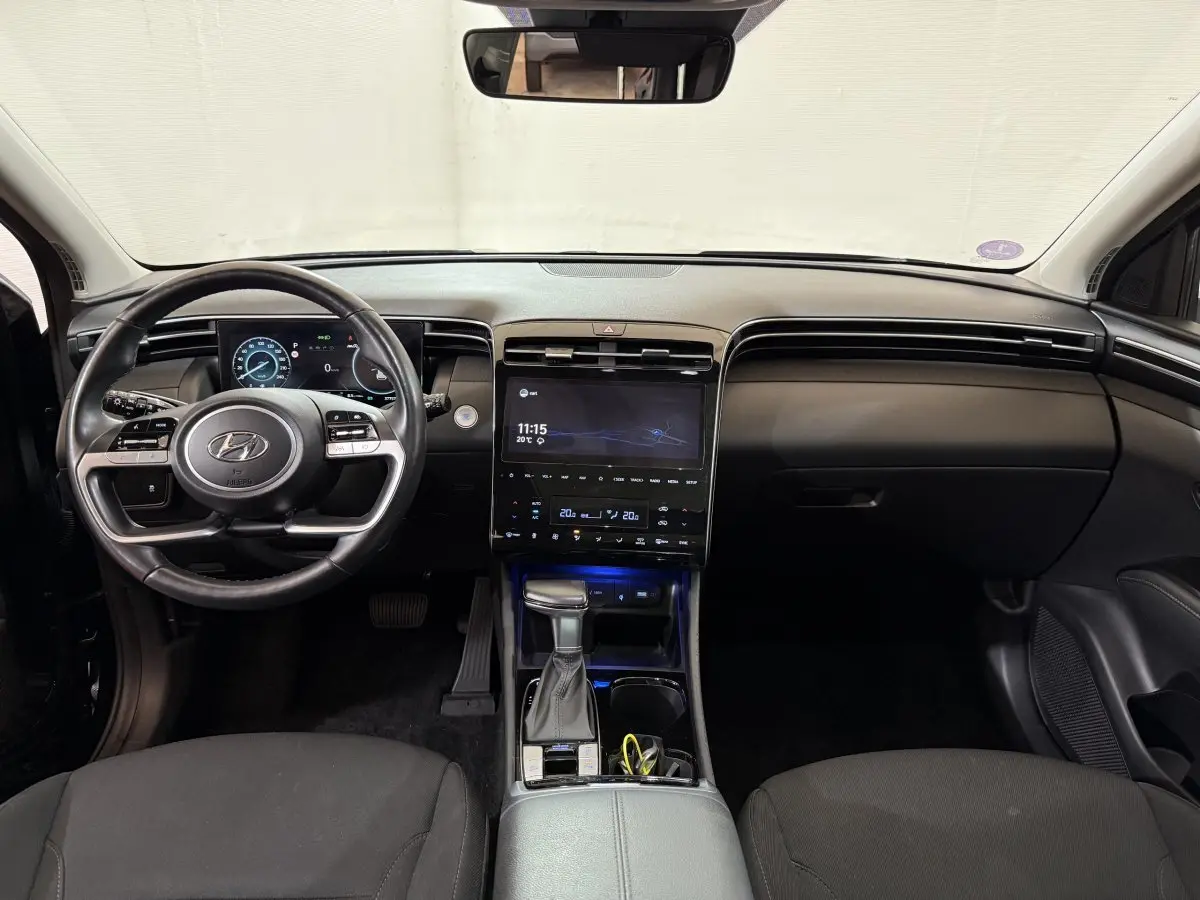 Vue intérieure avant du Hyundai Tucson noir 2021, tableau de bord moderne avec écran tactile central et volant multifonction.