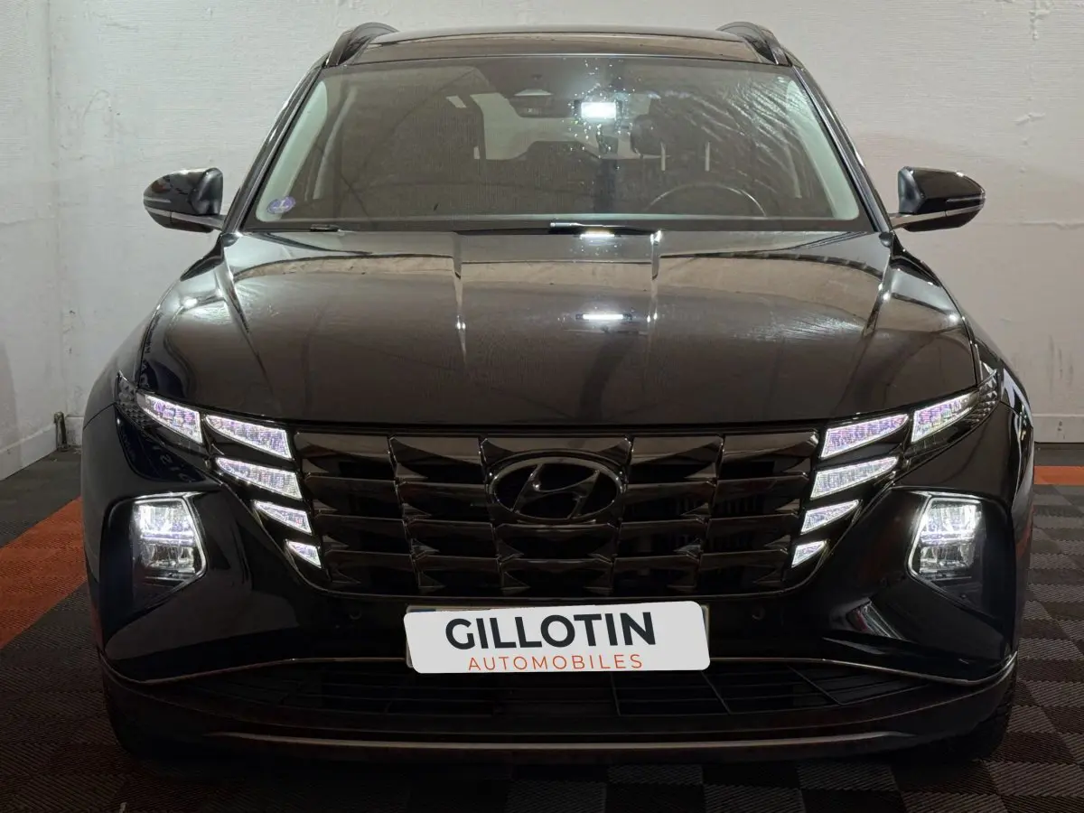 Vue frontale d'un Hyundai Tucson noir 2021 avec phares LED et calandre distinctive allumée.