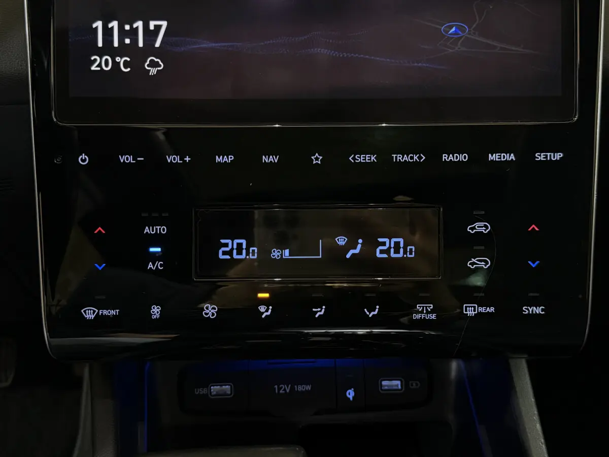 Gros plan sur la console centrale tactile du Hyundai Tucson noir, affichant la climatisation et commandes multimédia.