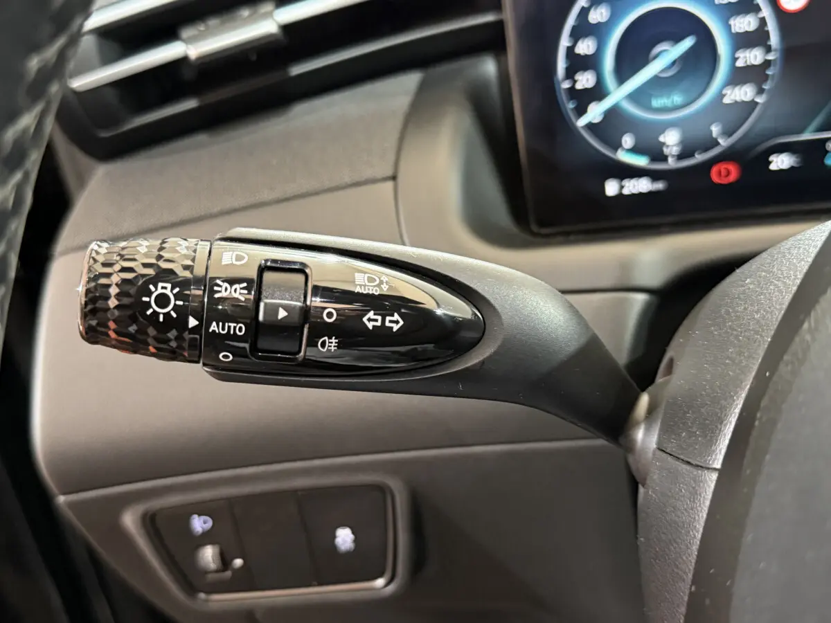 Gros plan sur la commande des feux et clignotants noire dans l'habitacle du Hyundai Tucson 2021 hybride noir.