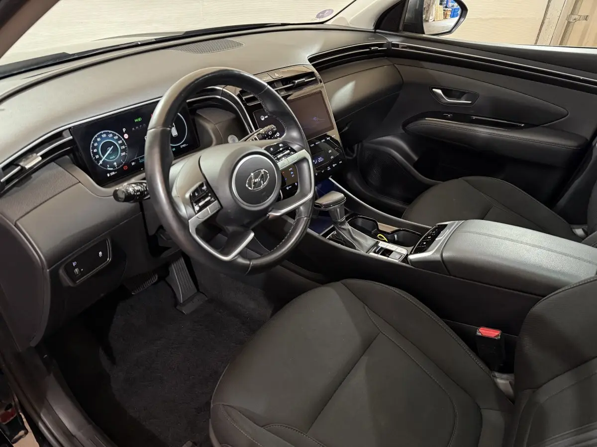 Intérieur noir du Hyundai Tucson 2021, vue côté conducteur sur le tableau de bord et la console centrale moderne.