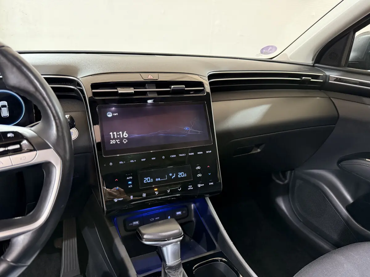 Vue intérieure côté conducteur du tableau de bord noir du Hyundai Tucson 2021 avec écran tactile et levier de vitesse automatique.