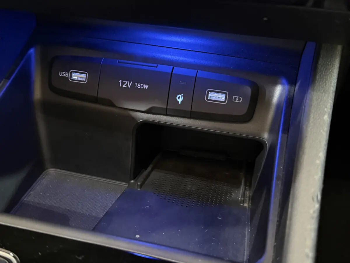 Gros plan sur la console centrale noire du Hyundai Tucson 2021, montrant ports USB, prise 12V et chargeur à induction.