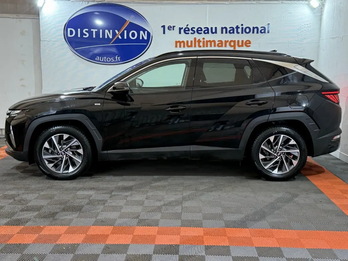 Profil côté gauche d'un Hyundai Tucson noir 2021 garé en intérieur avec jantes alliage et vitres teintées.