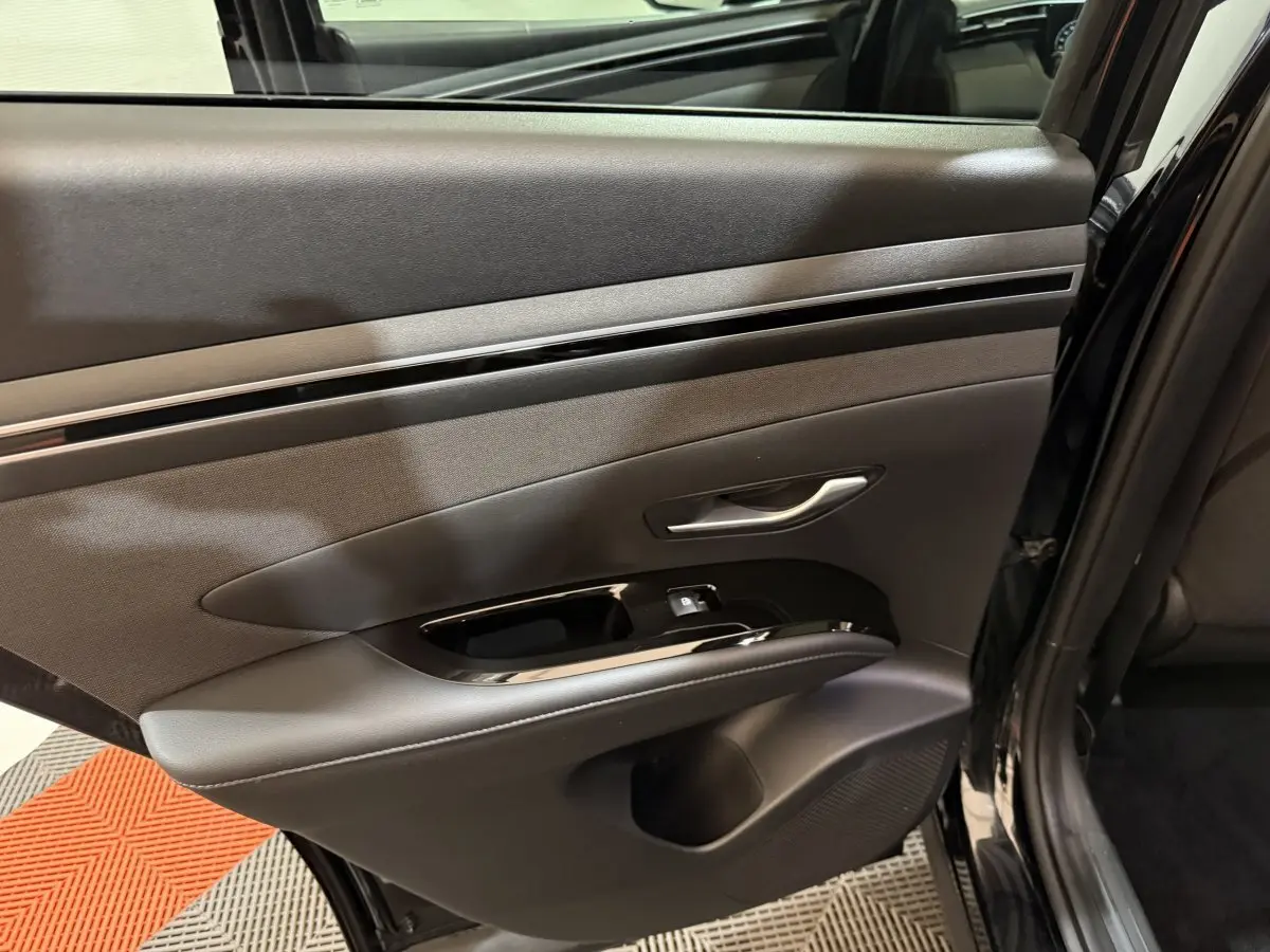 Vue côté gauche de la porte arrière noire du Hyundai Tucson 2021 avec poignée argentée et commande de vitre.
