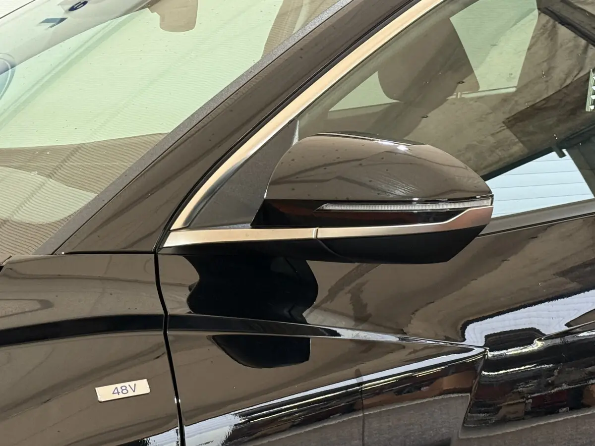 Gros plan sur le rétroviseur côté gauche noir brillant du Hyundai Tucson hybride 48V avec badge 48V visible sur la porte.
