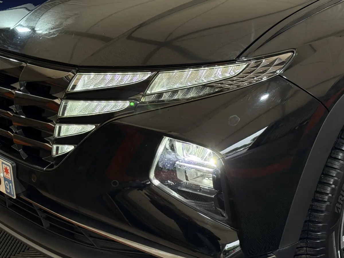Gros plan sur l'avant droit noir du Hyundai Tucson 2021, mettant en valeur ses phares LED et sa calandre distinctive.