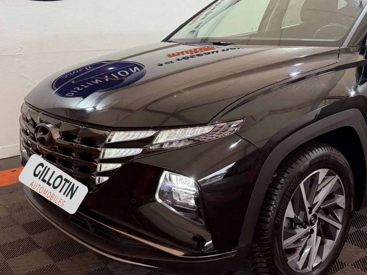 Vue 3/4 avant droit du Hyundai Tucson noir avec calandre distinctive et phares LED allumés.