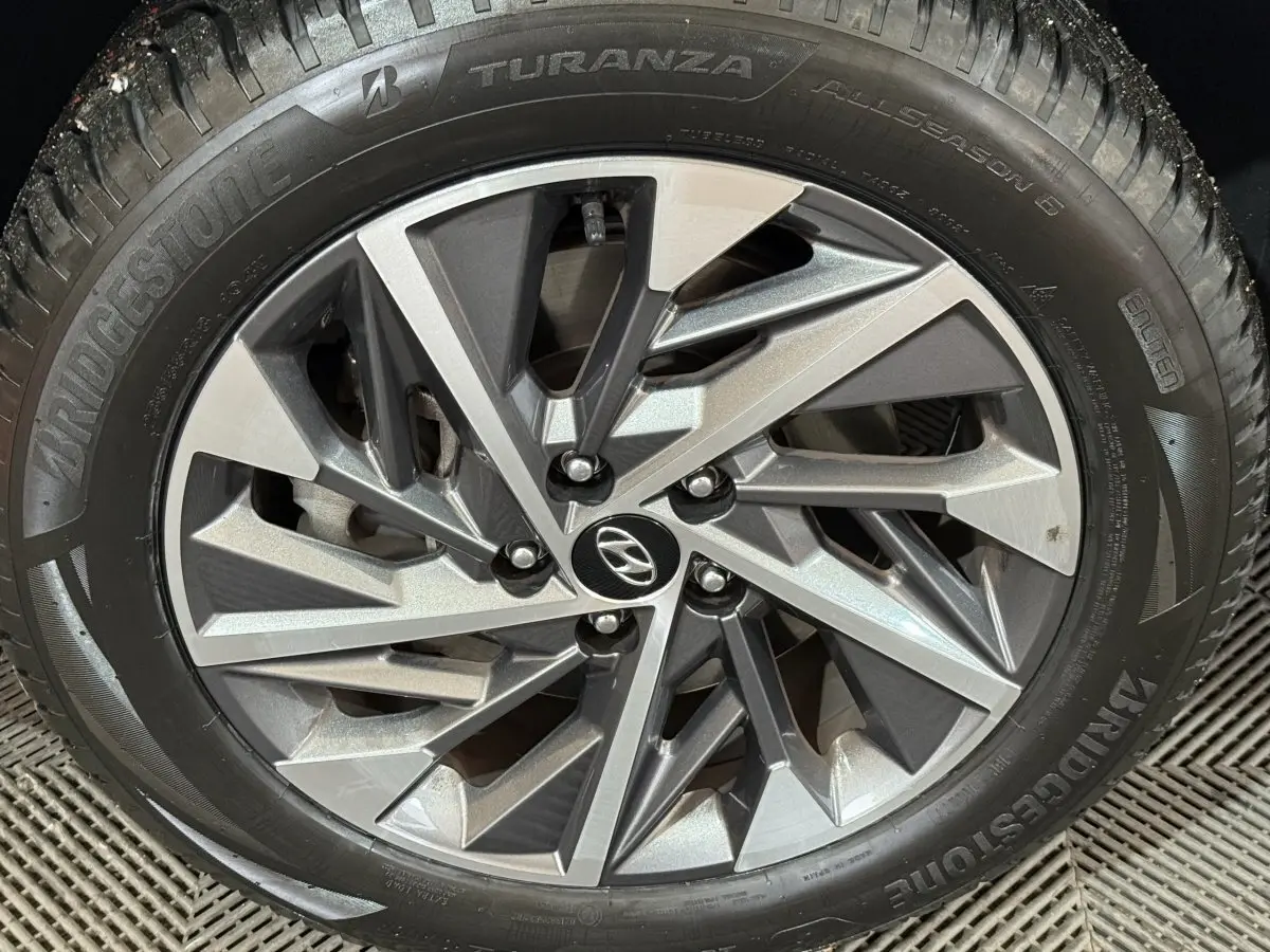 Gros plan sur la jante alliage argentée du Hyundai Tucson noir, pneu Bridgestone Turanza visible autour.