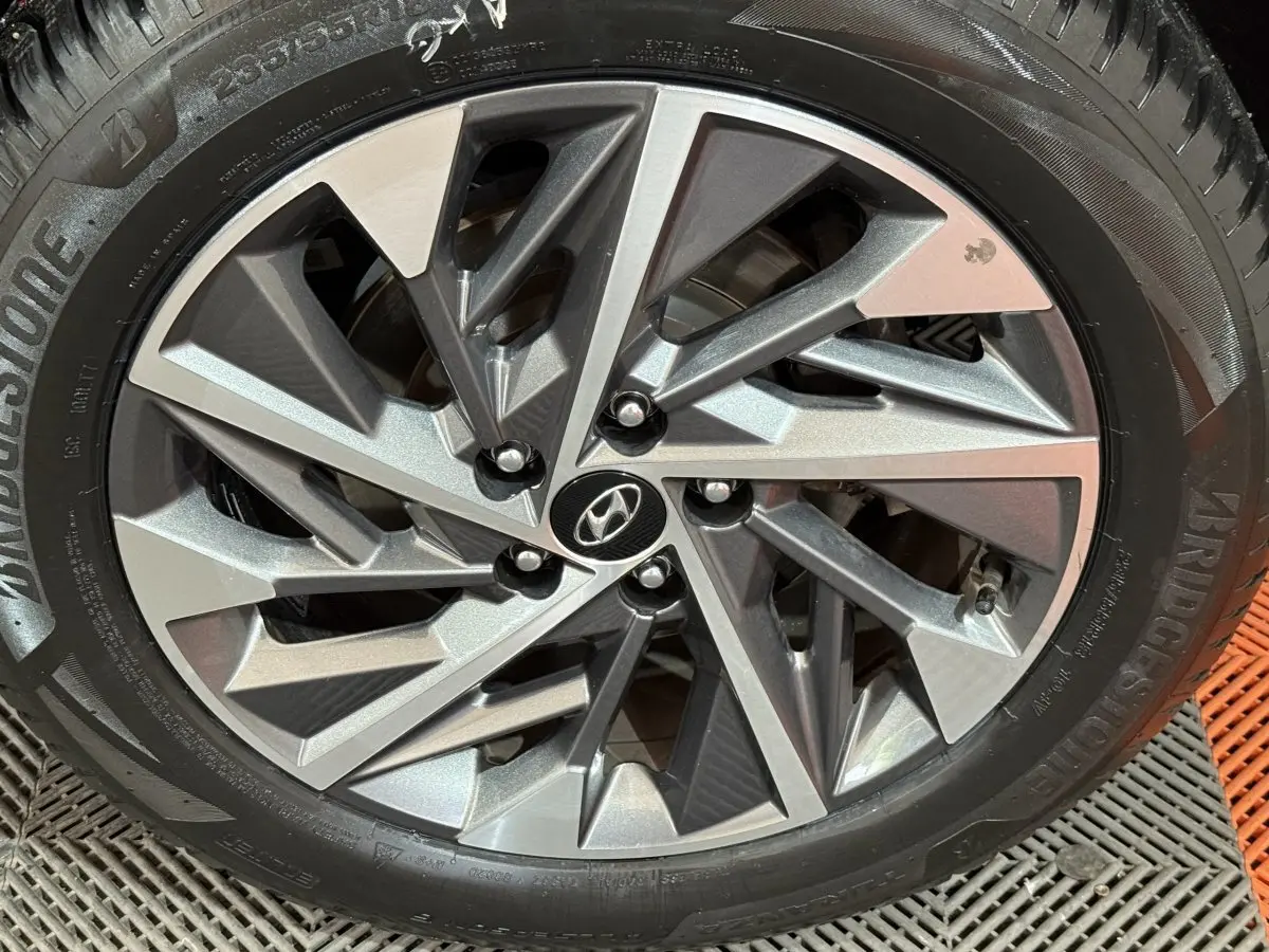 Gros plan sur la jante alliage au design géométrique du Hyundai Tucson noir 2021, roue Bridgestone visible.