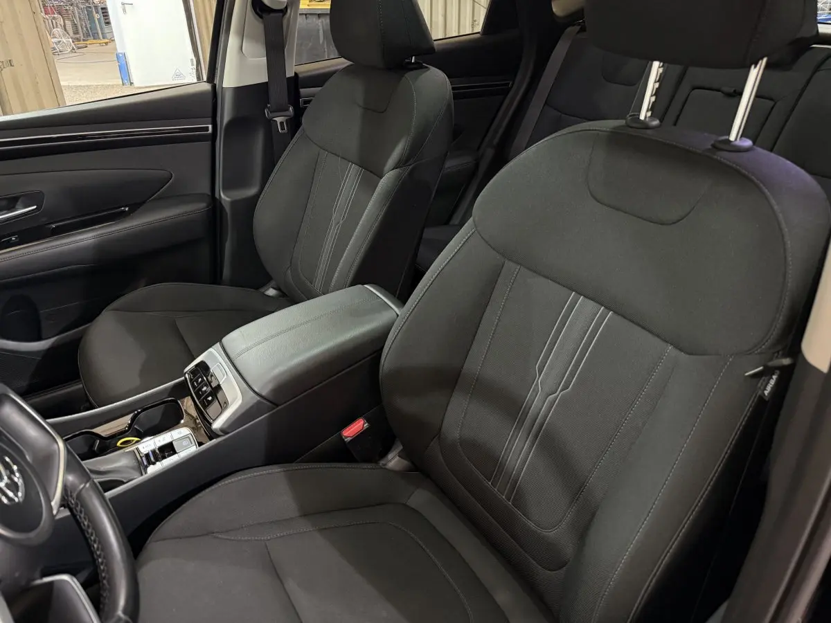 Intérieur noir du Hyundai Tucson 2021, vue rapprochée des sièges avant et console centrale moderne.