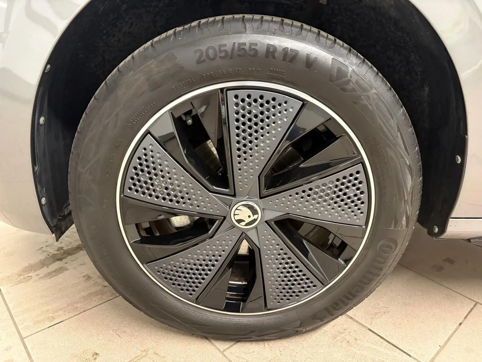 Gros plan sur la jante avant droite du Skoda Kamiq 2024 gris graphite, avec un design noir et gris perforé distinctif Monte Carlo.