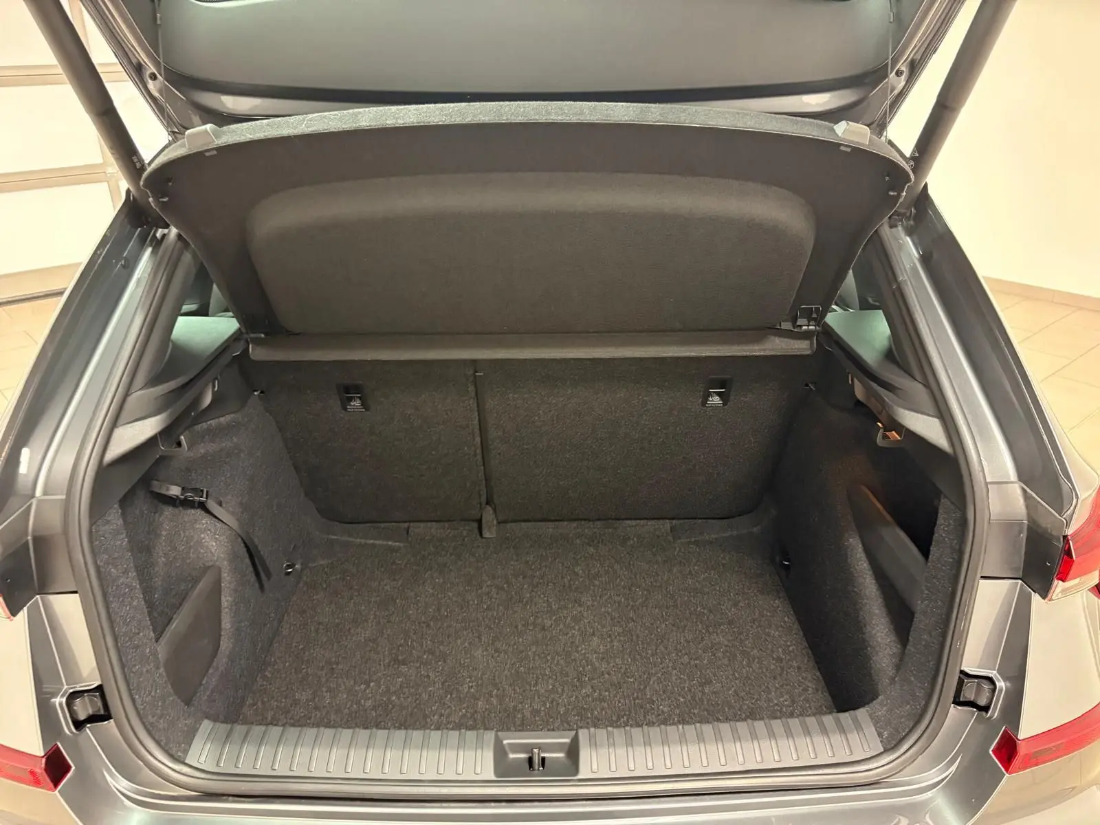 Coffre ouvert vu de l'arrière d'un Skoda Kamiq 2024 gris graphite, version Monte Carlo, montrant l'espace de chargement vide.