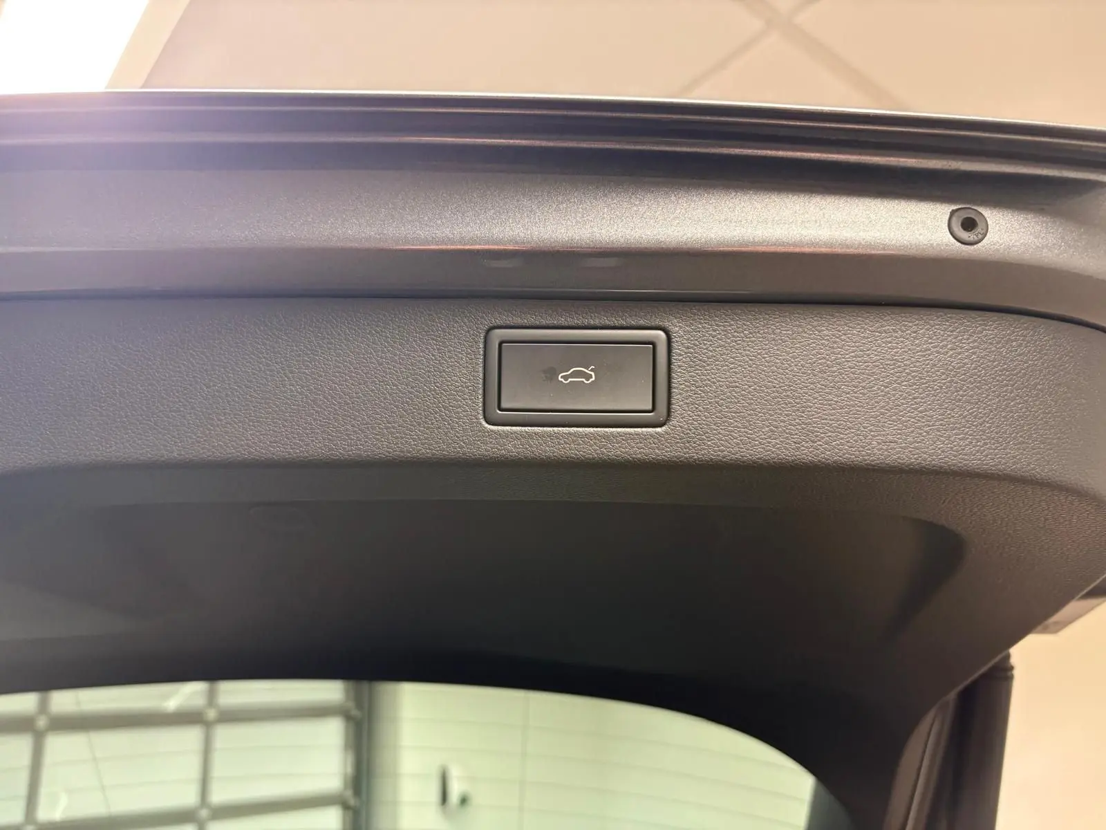 Bouton d'ouverture électrique du coffre sur la partie intérieure de la porte arrière d'un Skoda Kamiq gris graphite 2024.