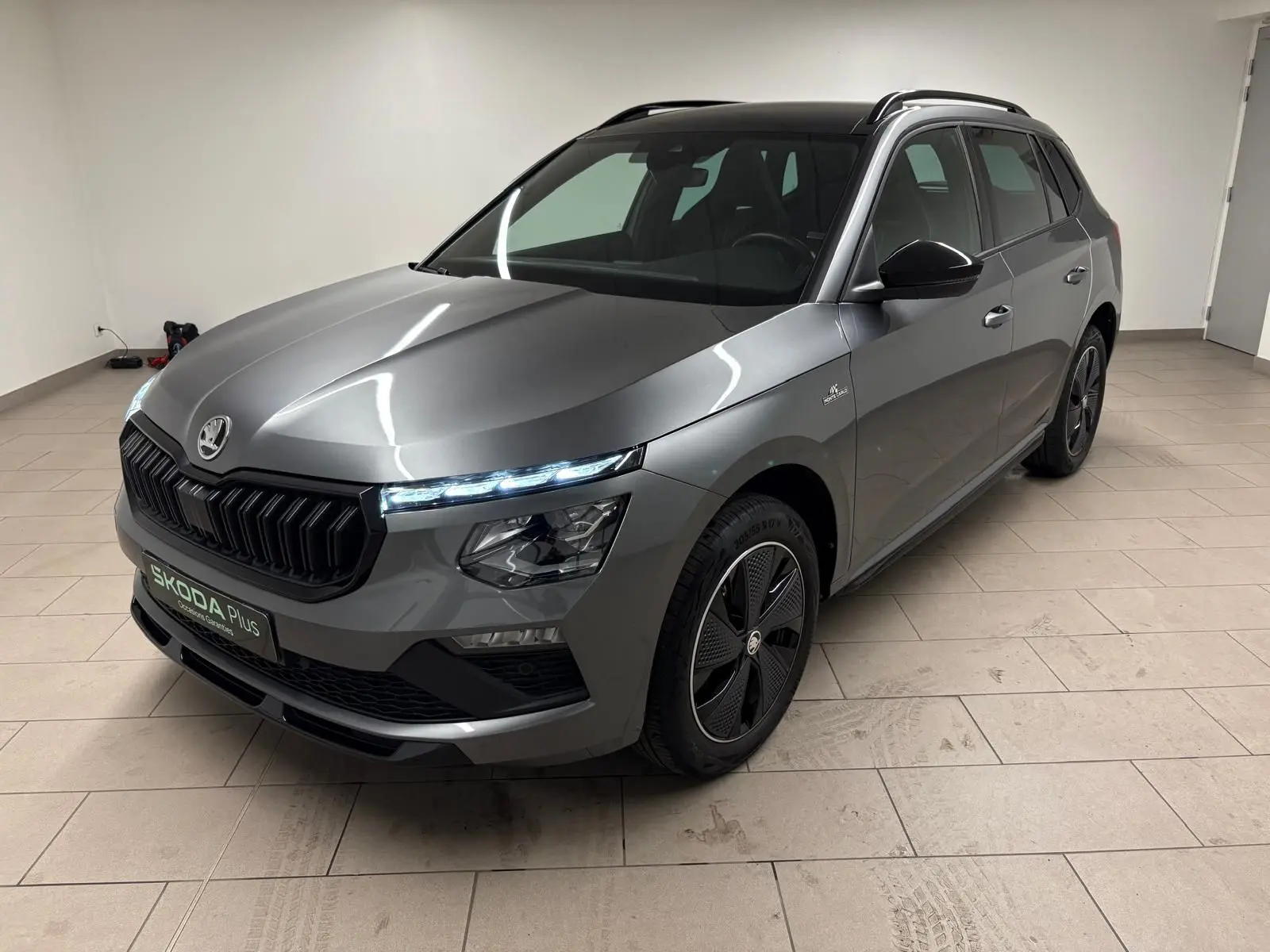 Skoda Kamiq Monte Carlo gris graphite vu en 3/4 avant droit, avec calandre noire et jantes spécifiques.