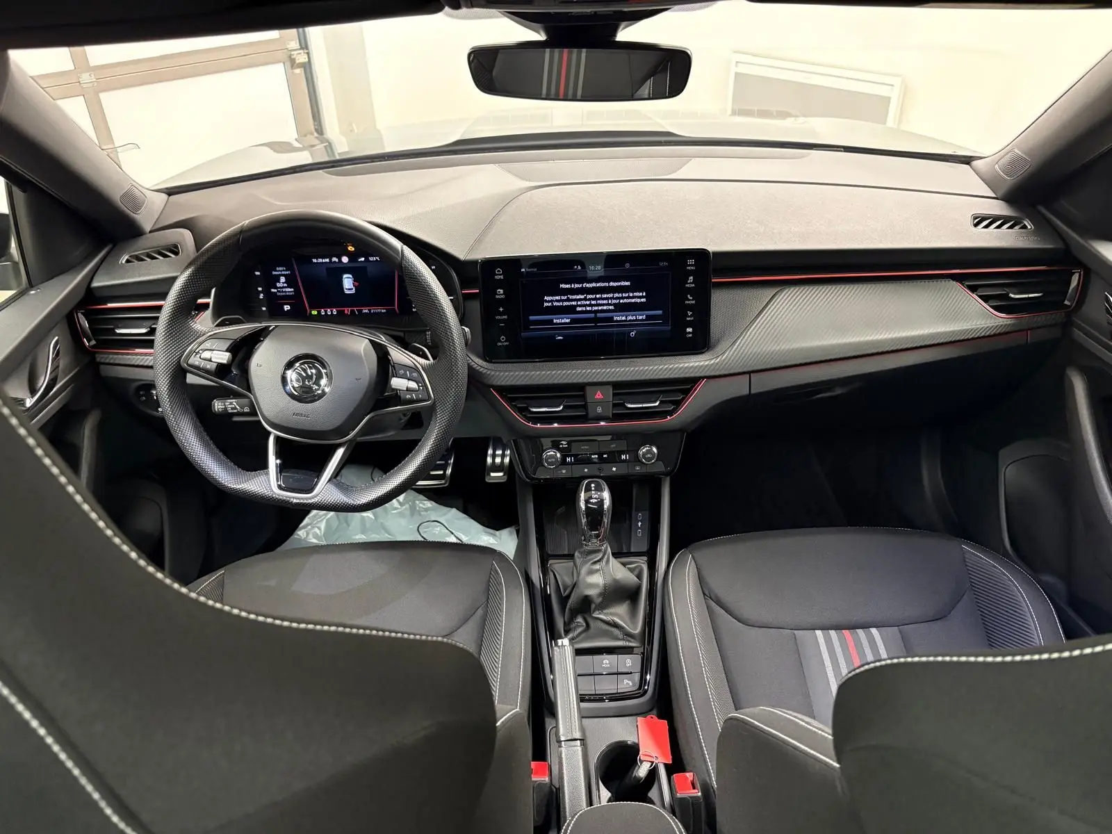 Vue intérieure avant du Skoda Kamiq Monte Carlo 2024, tableau de bord gris graphite avec touches rouges et volant multifonction.