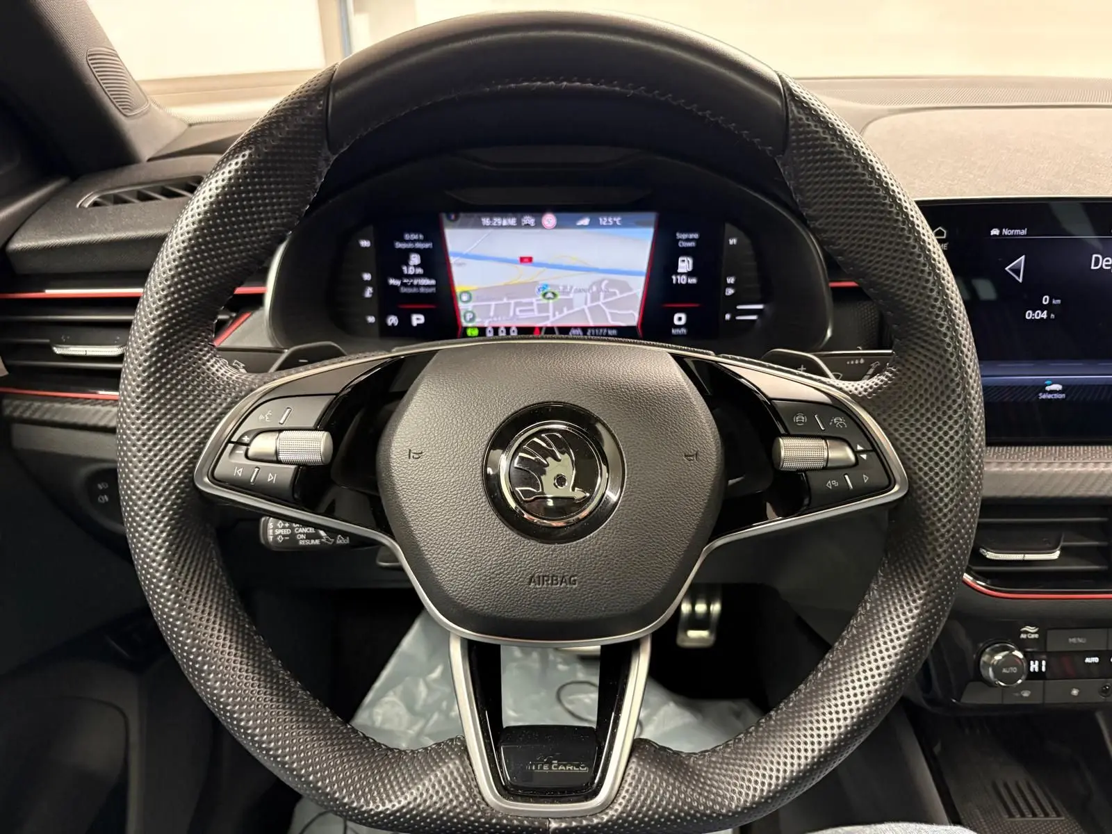 Vue rapprochée du volant perforé du Skoda Kamiq Monte Carlo 2024 avec tableau de bord numérique et détails en gris graphite.