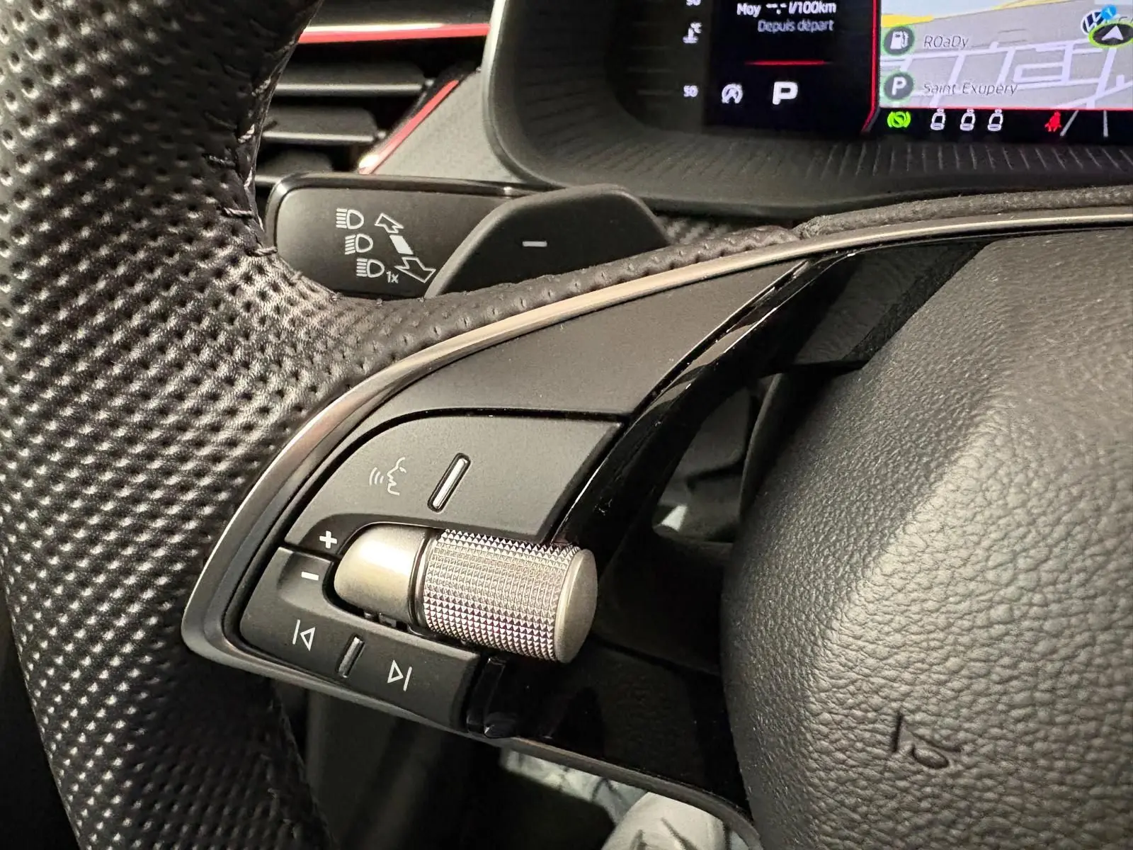 Gros plan sur les commandes gauche du volant perforé du Skoda Kamiq 2024 Monte Carlo, avec molette métallique et tableau de bord numérique.