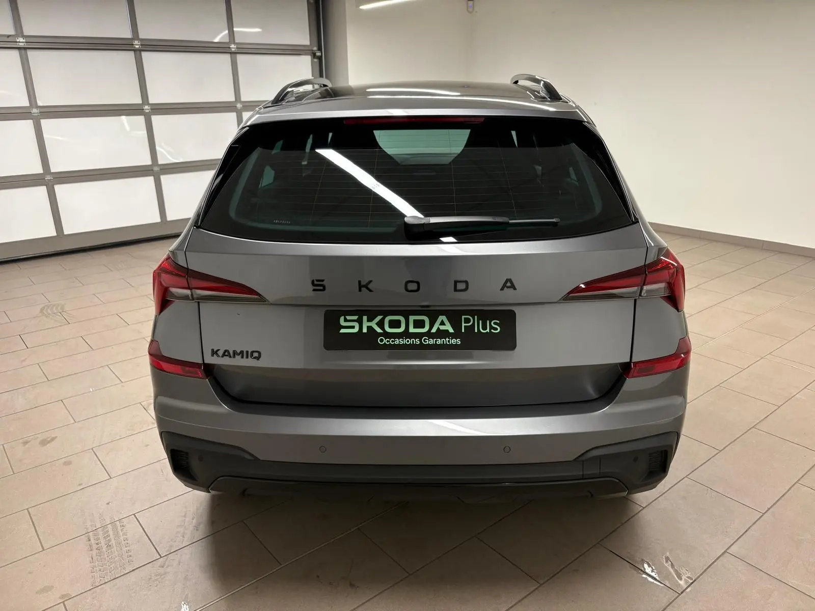 Vue arrière d'un Skoda Kamiq 2024 gris graphite, avec logo SKODA et feux arrière LED distinctifs en intérieur.