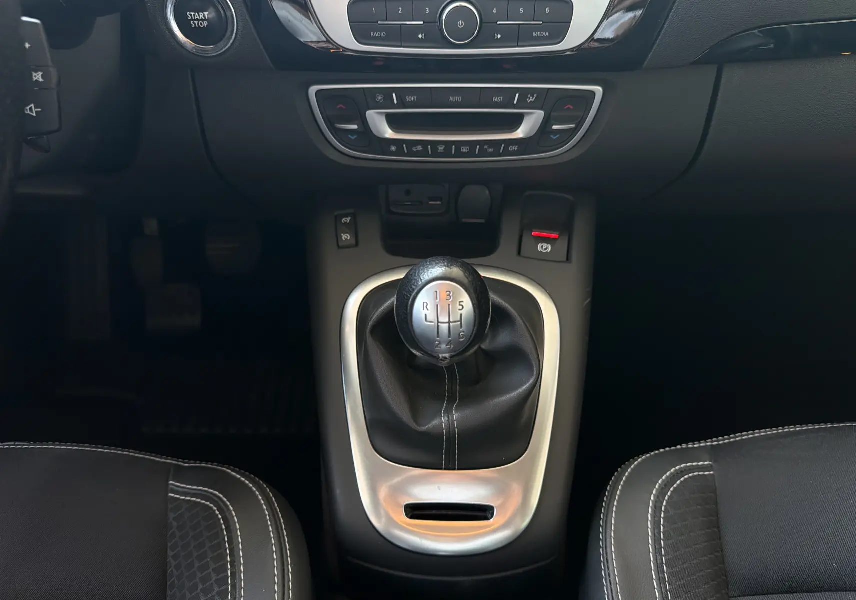 Vue rapprochée du levier de vitesses manuel et de la console centrale noire du Renault Scénic gris Cassiopée 2015.