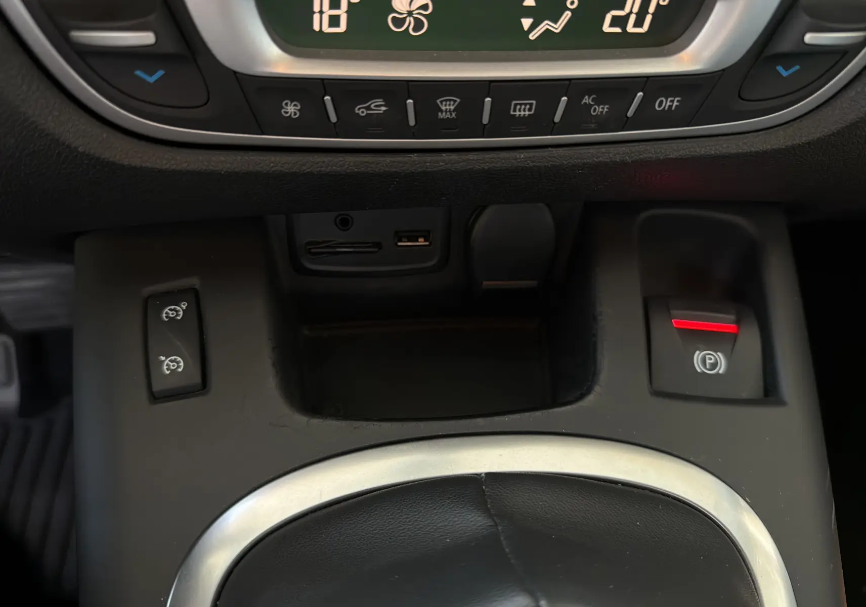Détail de la console centrale du Renault Scenic gris Cassiopée 2015, avec commandes climatisation et frein à main électrique.